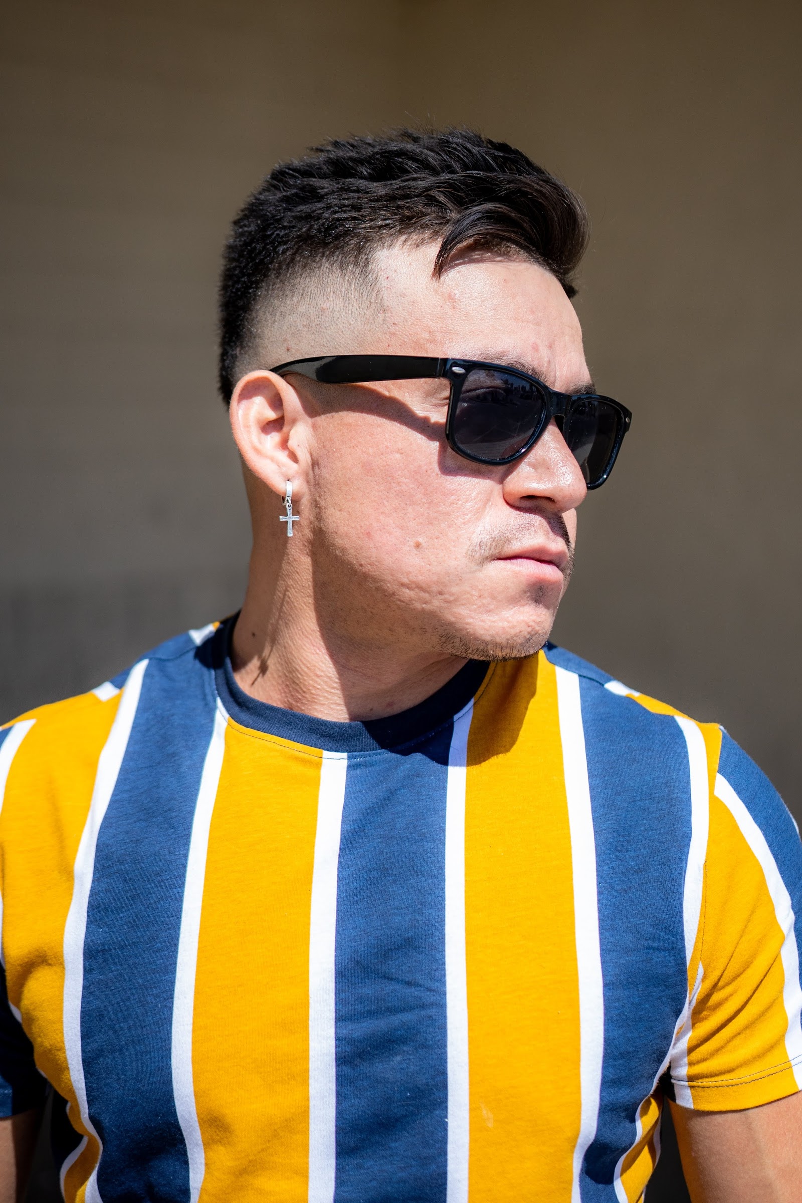 Man with a mid fade haircut wearing sunglasses in bright sunlight